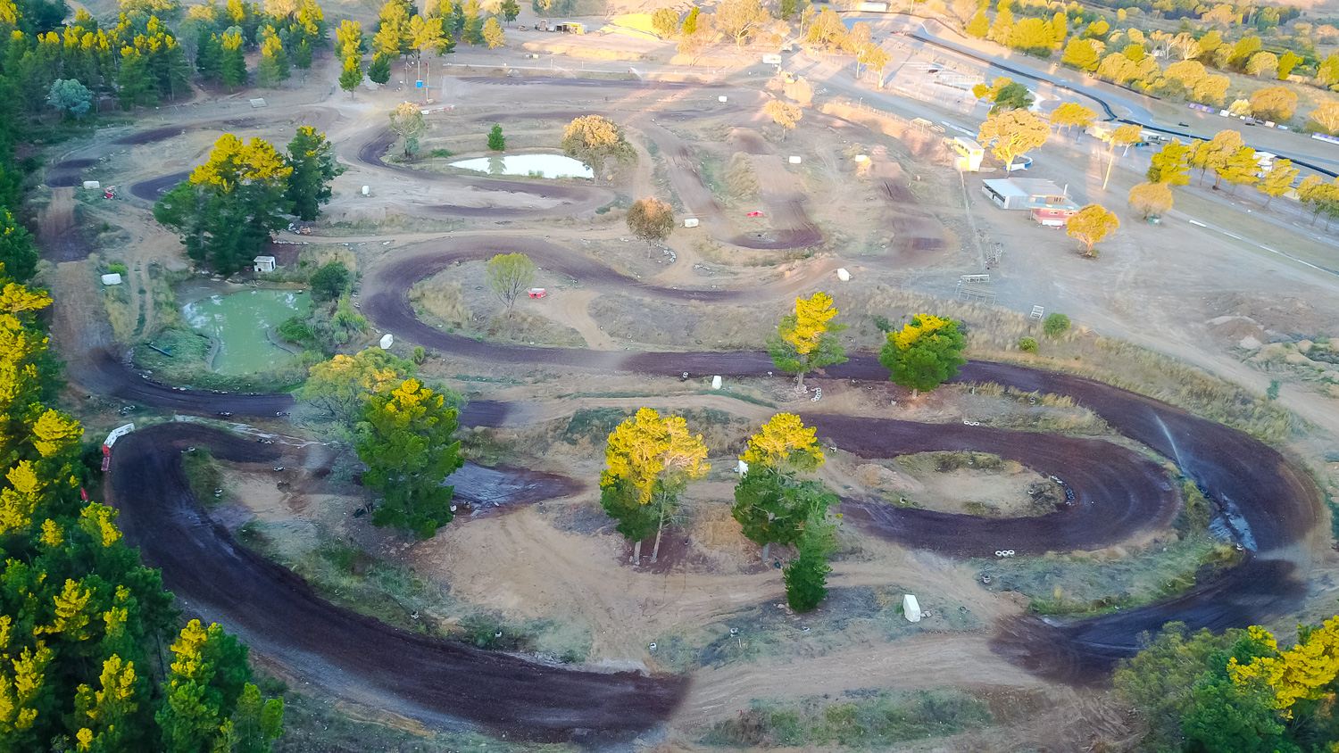 A motocross rider navigating a high-speed turn on the red clay track at the ACT Motorcycle Club main circuit
